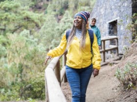 solo woman traveler in yellow jacket walking along mountain path