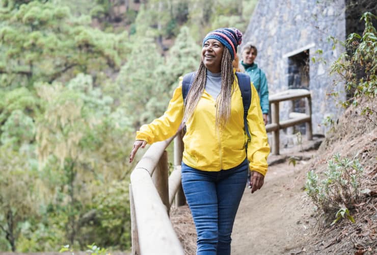 solo woman traveler in yellow jacket walking along mountain path