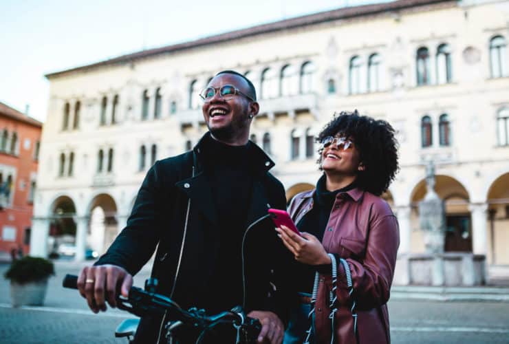 sightseeing couple holding bike and phone stop to look at a sight in an Italian city