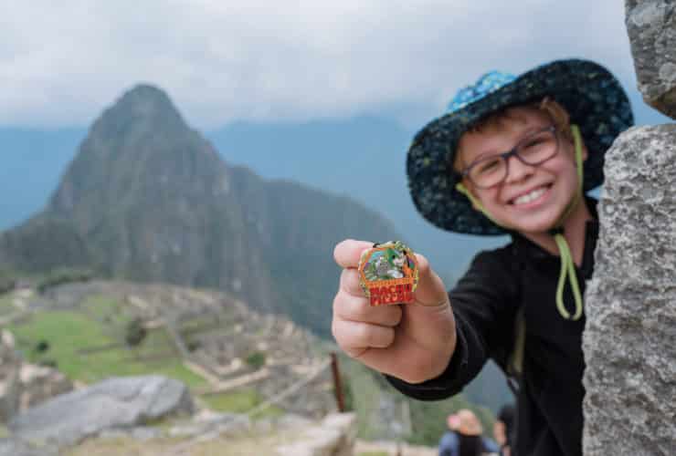child holding a Adventures by Disney Machu Picchu pin in Machu Picchu