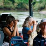two people looking through binoculars on a boat during a Road Scholar tour to Costa Rica