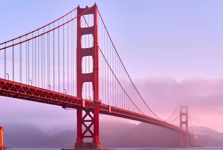 view of the Golden Gate bridge and Fort Point at sunrise with light fog