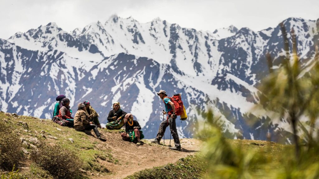 Trekking tour in West Nepal, hiker walking in the mountains past a group of local people