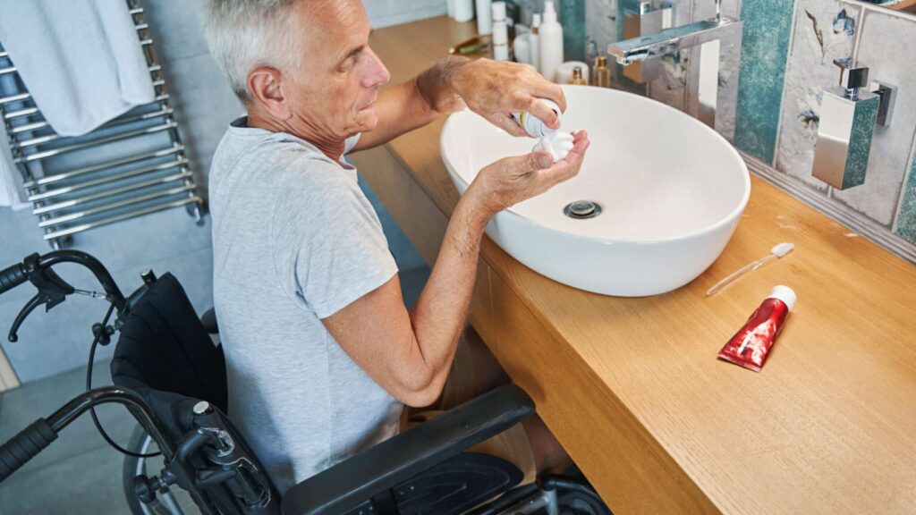 man in wheelchair getting ready to shave at the bathroom sink