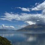 View of water and mountains with puffy clouds and blue skies on Adventures by Disney tour in New Zealand