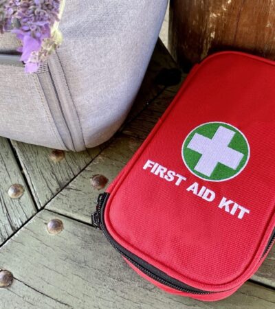 Travel first aid kit next to backpack and small bouquet of lavender on park bench