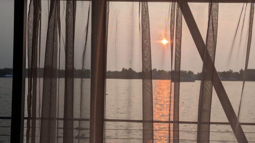 view of sunrise through sheer curtains aboard CroisiEurope Mekong River cruise