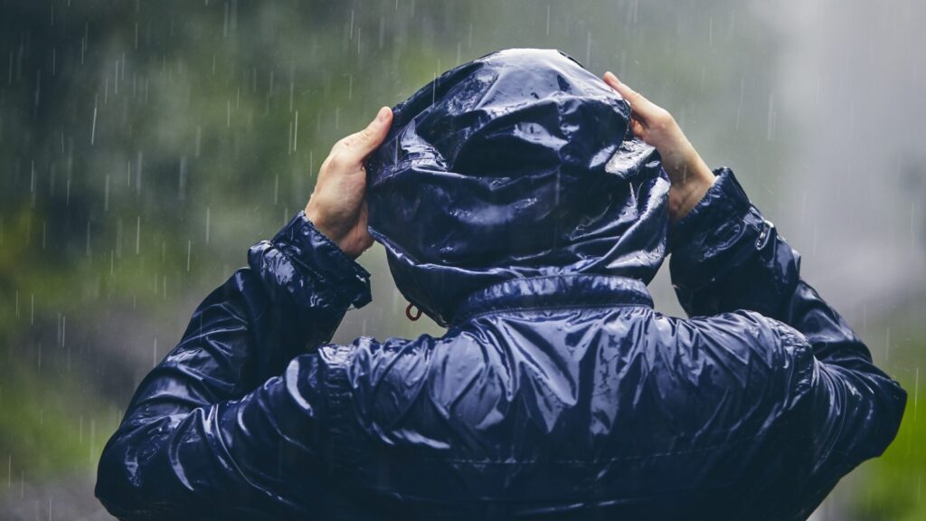 person wearing blue packable rain jacket in a heavy downpour