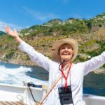 A woman happily raising her arms while on a boat while on a Road Scholar tour