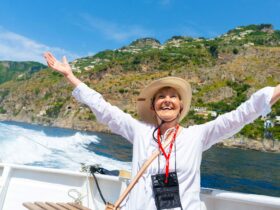 A woman happily raising her arms while on a boat while on a Road Scholar tour