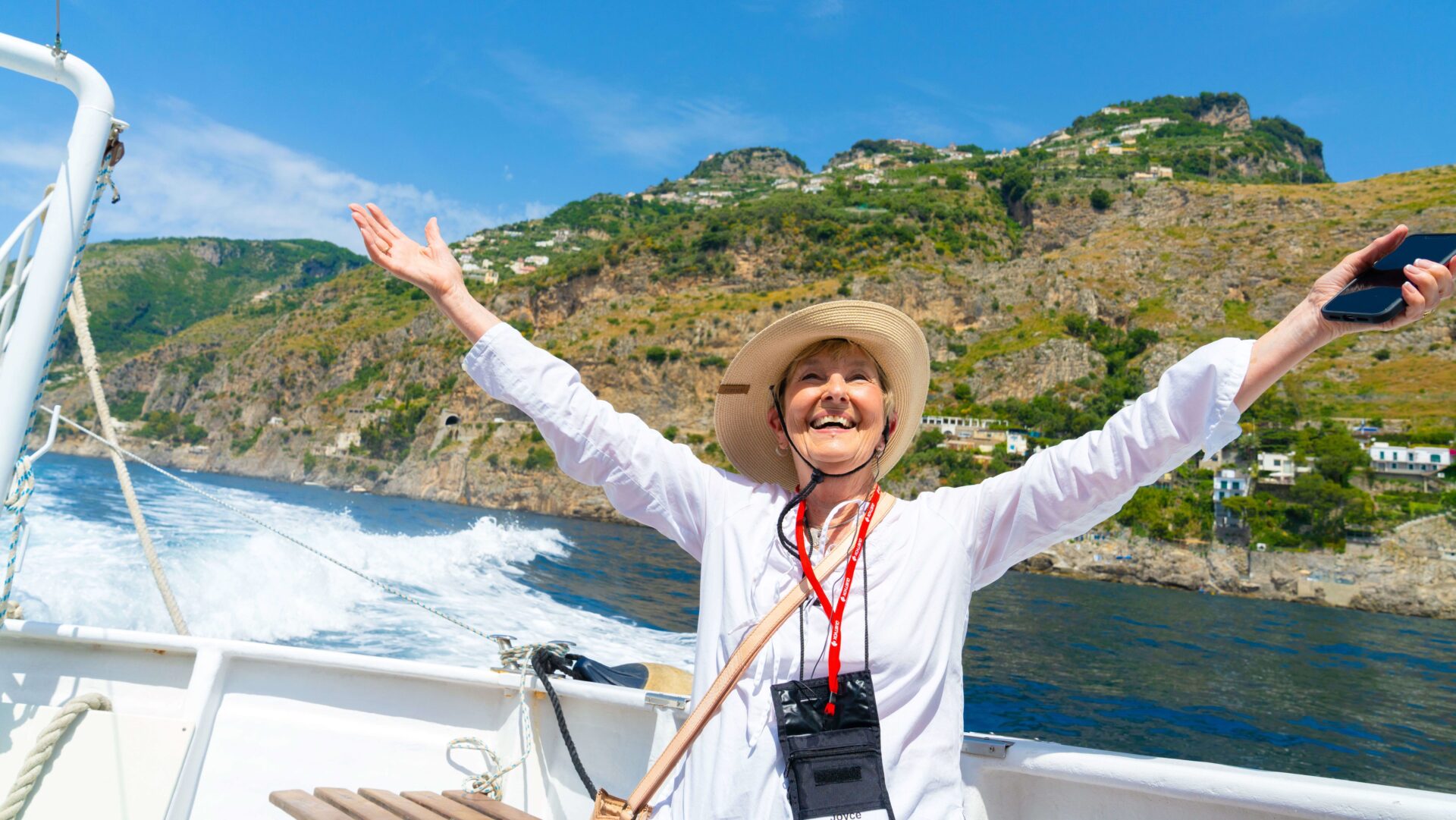 A woman happily raising her arms while on a boat while on a Road Scholar tour