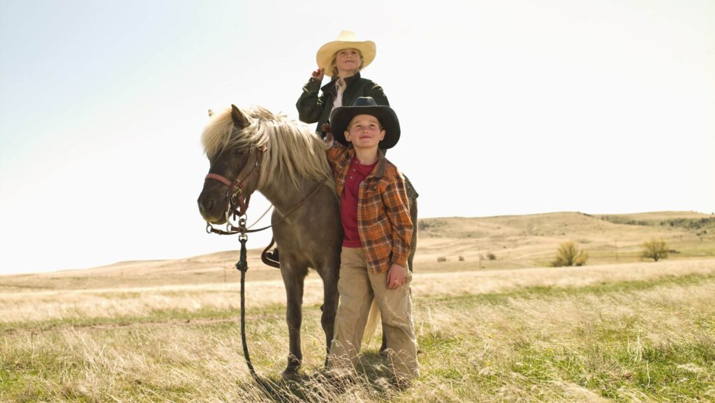 Young cowgirl and cowboy with pony on family ranch in Big Timber, Montana on a Trafalgar Wild West, Cowboys, and Buffalo tour