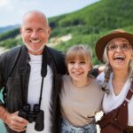 A happy preteen girl with grandparents on hiking trip on summer holiday, looking at camera.
