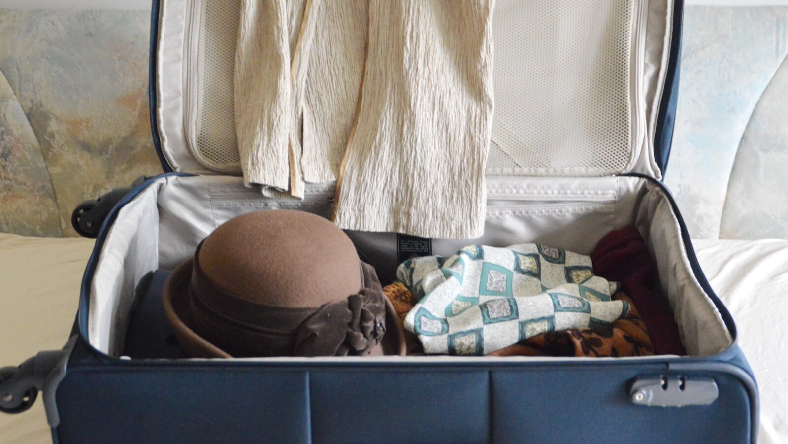 partially packed suitcase with hat