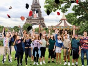 kids on a tauck bridges tour in Paris throwing their berets in the air in front of the Eiffel Tower