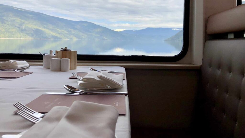 Table in the dining room of Rocky Mountaineer with beautiful mountains and lake in background