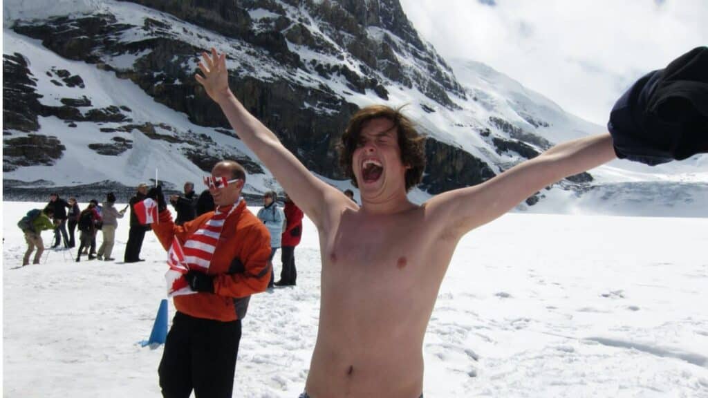 teenager on Adventures. by Disney tour experiencing Columbia ice field and the cold temperatures by taking off his shirt