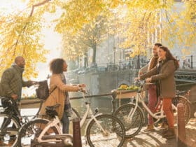 Friends with bicycles along sunny autumn canal in Amsterdam