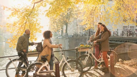 Friends with bicycles along sunny autumn canal in Amsterdam