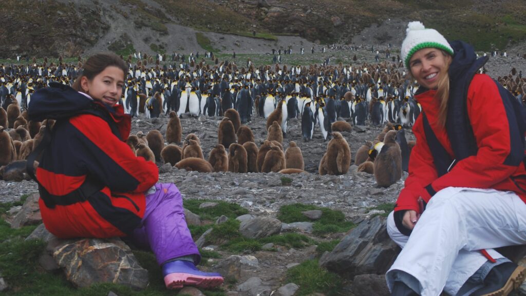 parent and child next to a colony of penguins on an Abercrombie & Kent tour