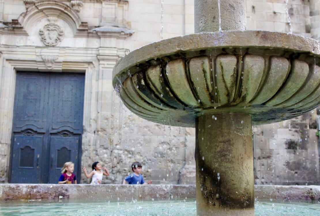 kids running behind fountain in the Barrio Gotico in Barcelona, Spain