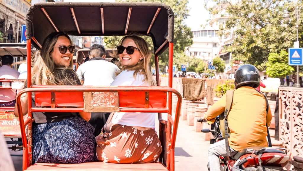 two young travelers on a Contiki tour in Delhi looking out of a tuk tuk