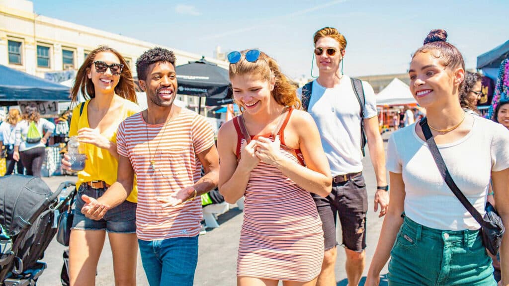 Young adults walking around a farmer's market on a sunny day