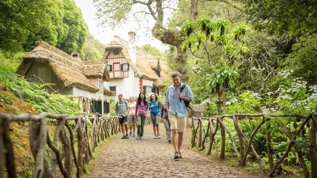 A group of people walking near a cottage in the countryside on a Globus tour
