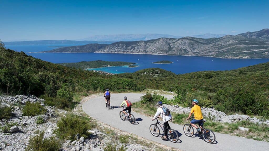 Four people riding bikes on a path overlooking water on an Exodus tour