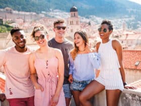 Young adults standing on a rooftop with an ancient city and mountains in the background