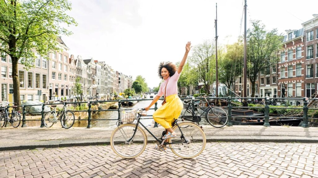 A woman riding a bike near a canal in Amsterdam with EF Go Ahead Tours