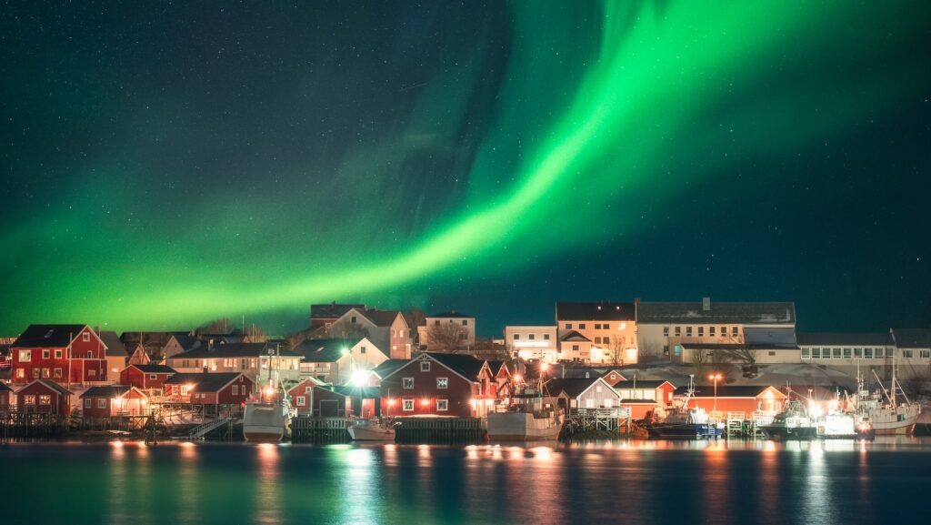 Northern lights over fishing village on coastline at Lofoten, Norway