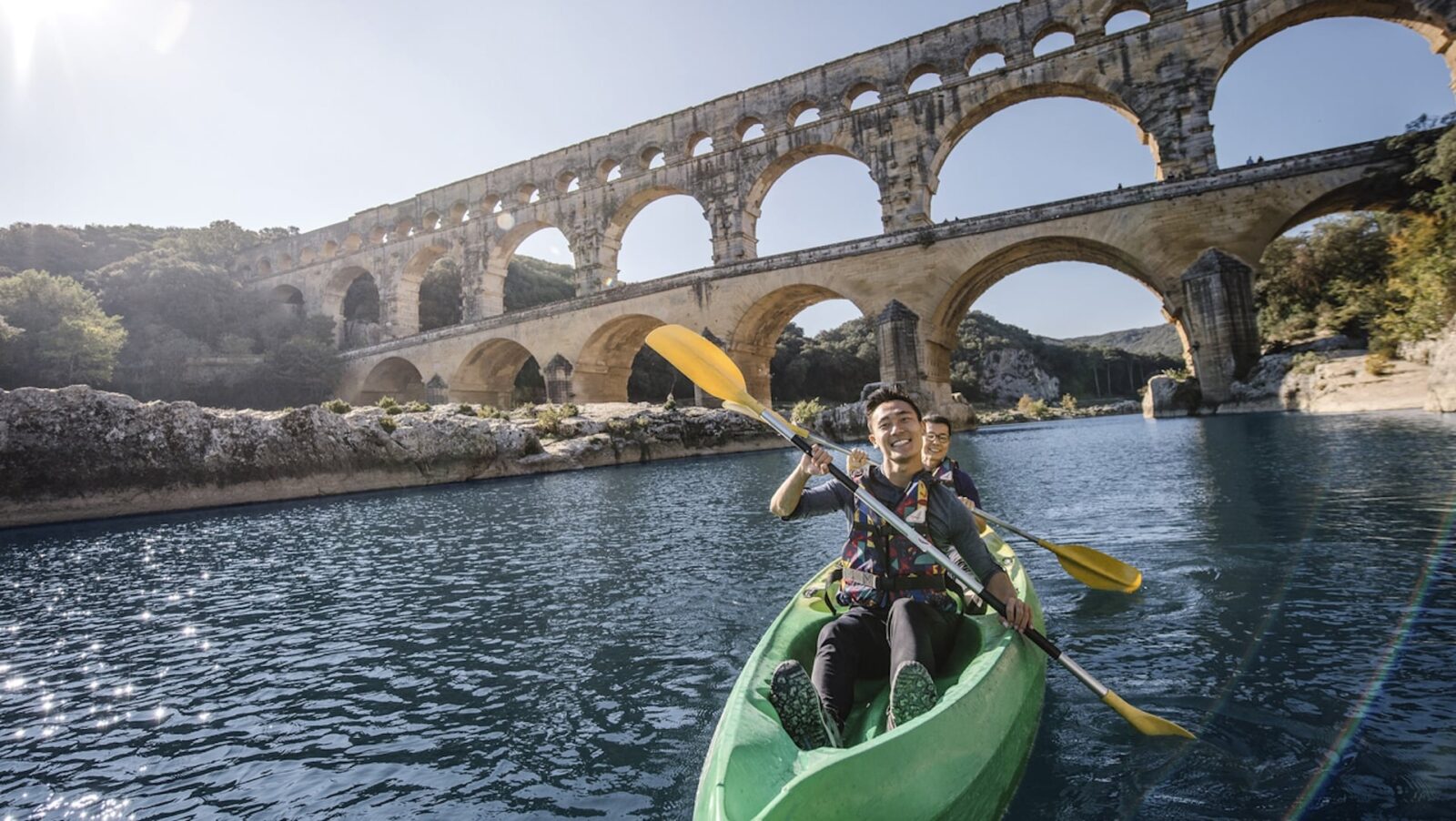 Two people kayaking under an arched bridge