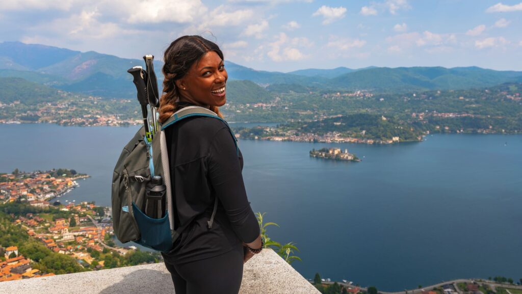 woman with hiking poles in backpack looking out over water on a Backroads trip