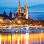 Uniworld/Trafalgar cruise ship on the Danube at night with cathedral in background