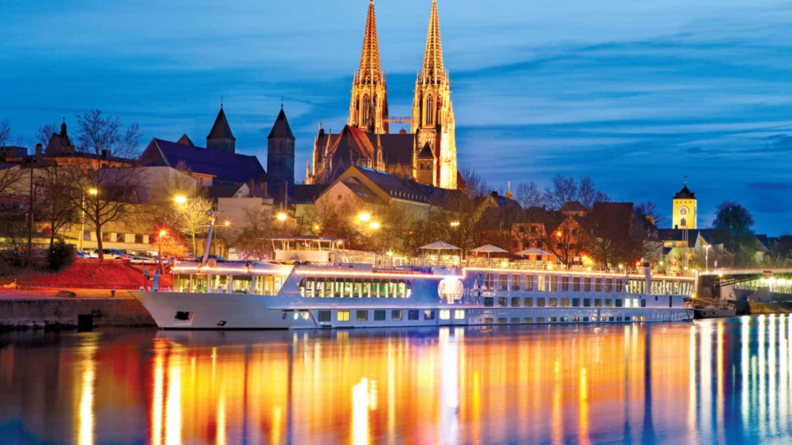 Uniworld/Trafalgar cruise ship on the Danube at night with cathedral in background