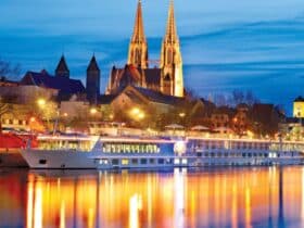 Uniworld/Trafalgar cruise ship on the Danube at night with cathedral in background