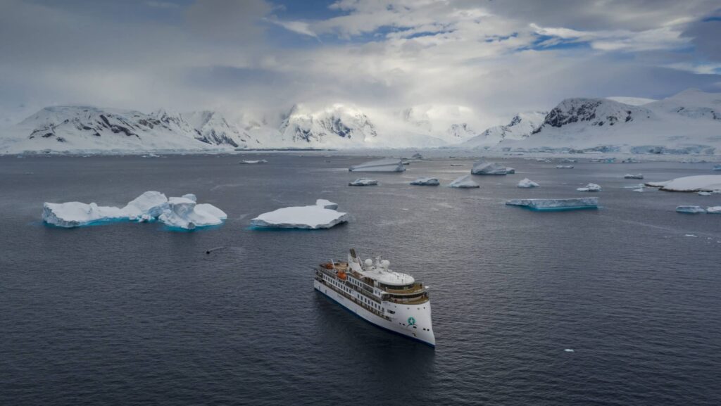 An aerial view of Aurora Expedition's Greg Mortimer ship among the ice and mountains in Antarctica