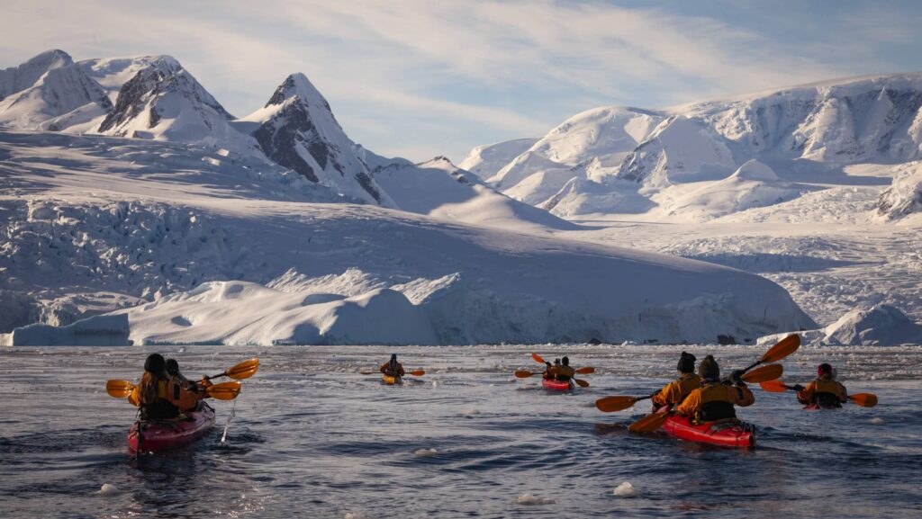 Travelers kayaking with mountains in the distance on a G Adventures Antarctica cruise