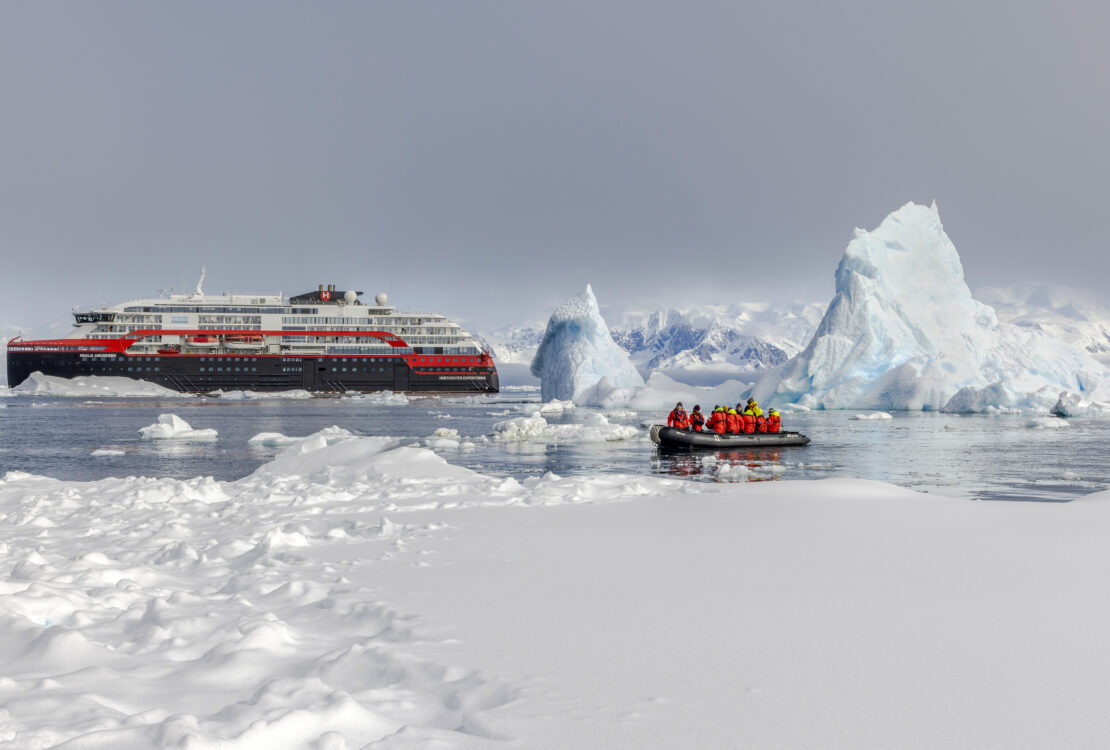 People on a Zodiac in icy waters near an HX Expeditions ship in Antarctica