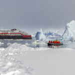 People on a Zodiac in icy waters near an HX Expeditions ship in Antarctica