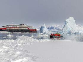 People on a Zodiac in icy waters near an HX Expeditions ship in Antarctica