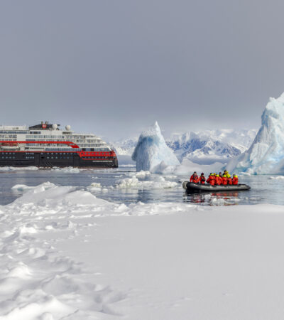 People on a Zodiac in icy waters near an HX Expeditions ship in Antarctica