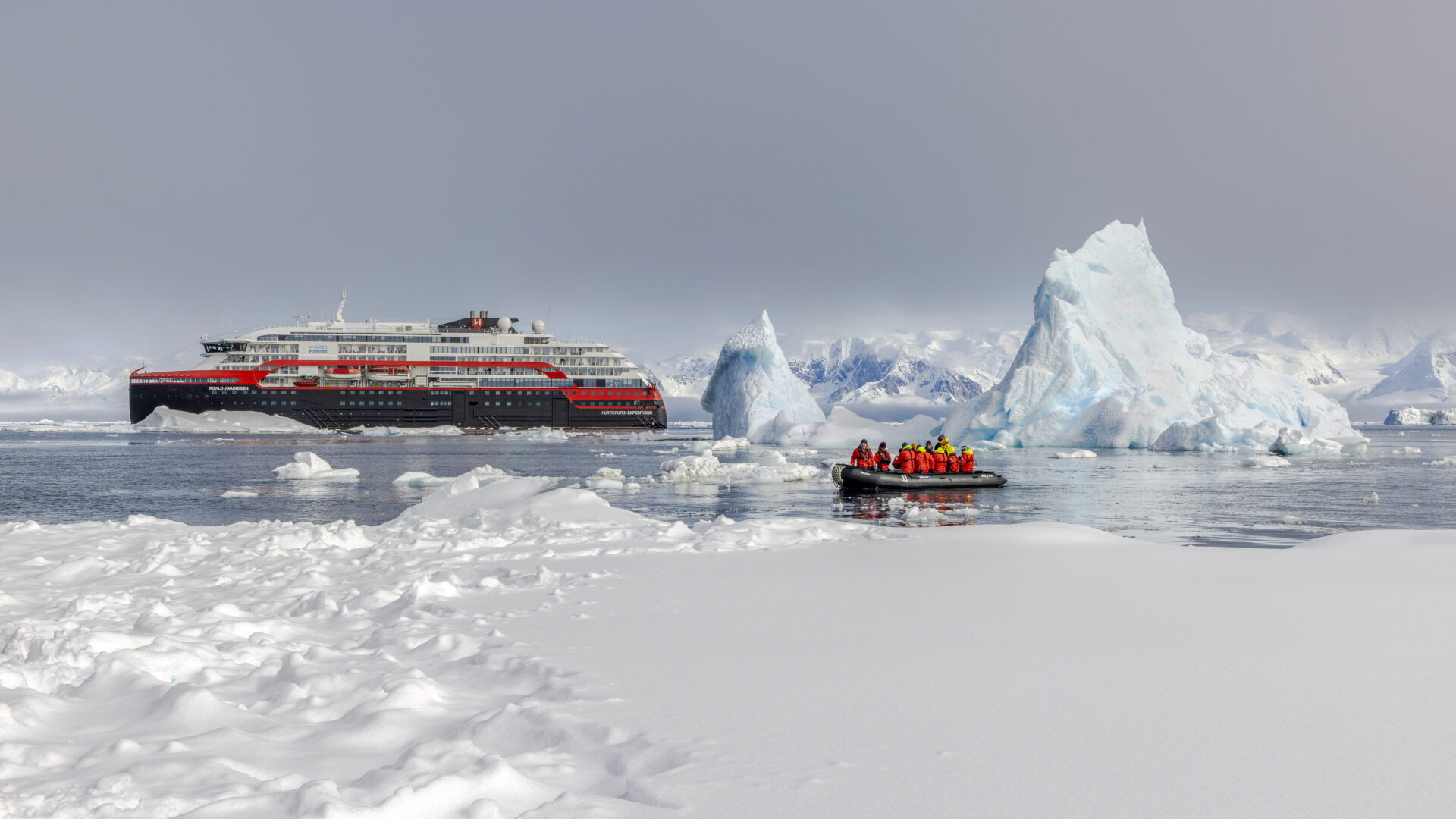 People on a Zodiac in icy waters near an HX Expeditions ship in Antarctica