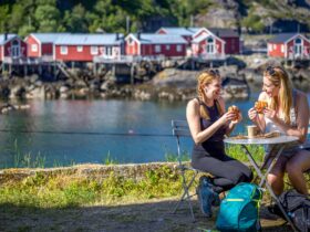 Two women eating in front of the water with red buildings behind them on a Backroads tour in Norway