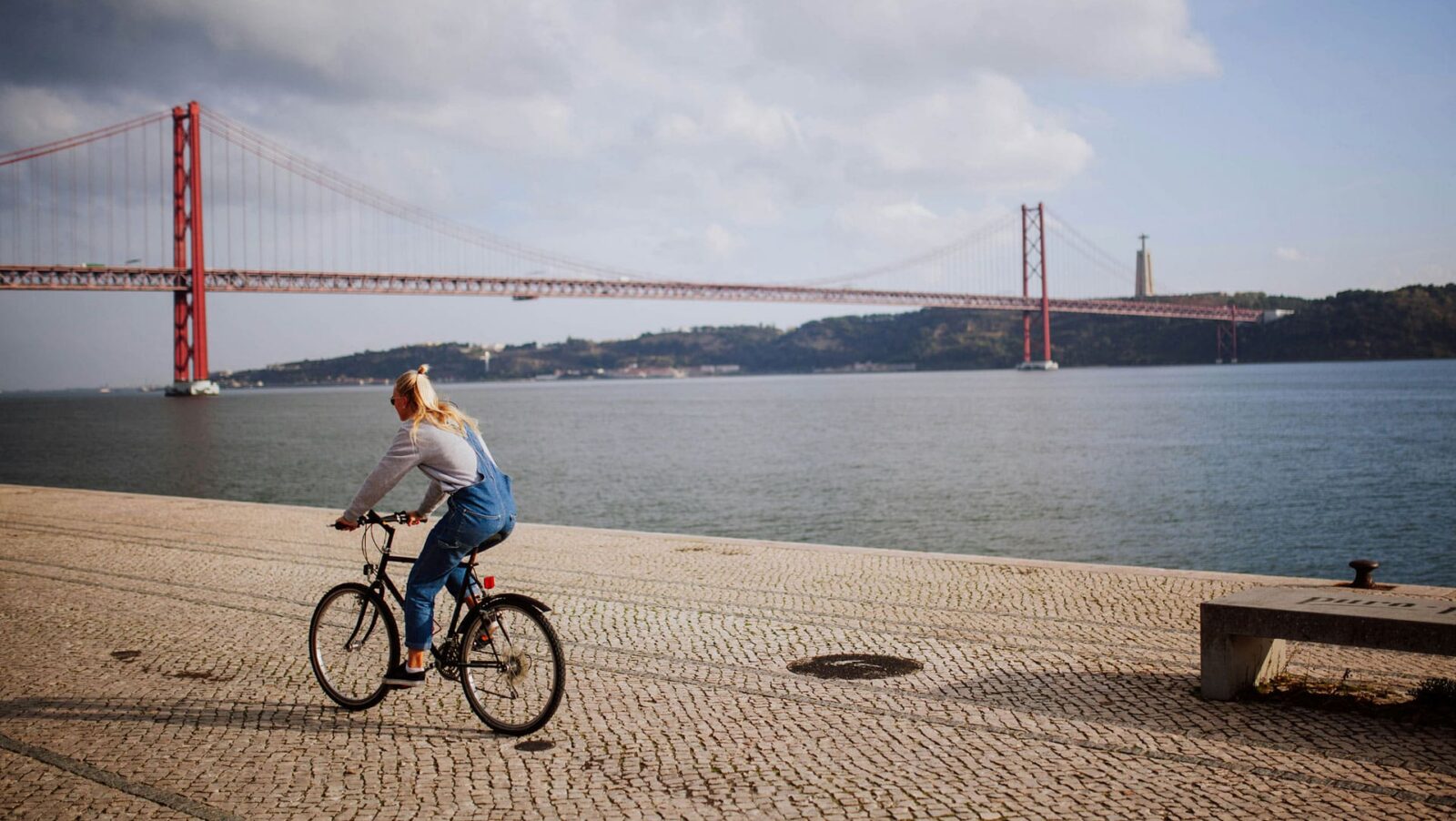 A woman riding a bike on a stone pathway near the Golden Gate Bridge