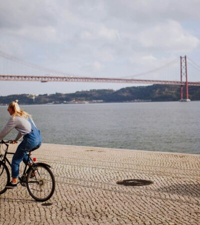 A woman riding a bike on a stone pathway near the Golden Gate Bridge
