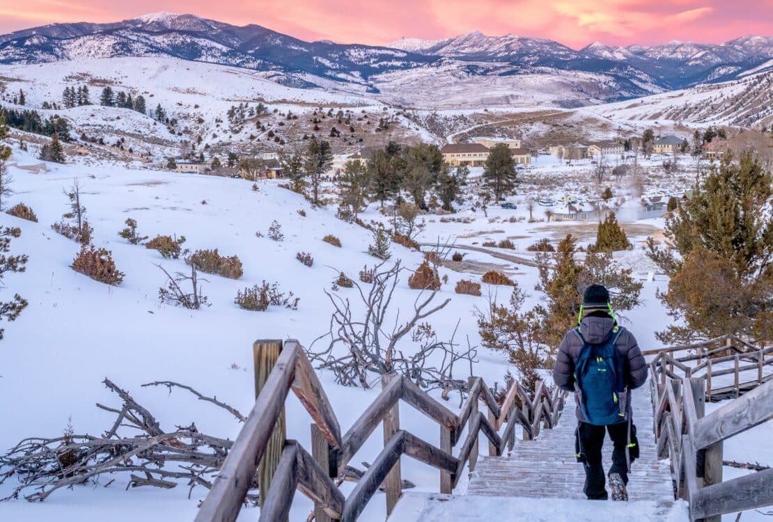 A backpacker walking down stairs at Yellowstone in the winter