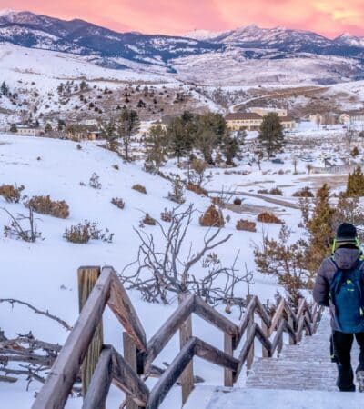 A backpacker walking down stairs at Yellowstone in the winter